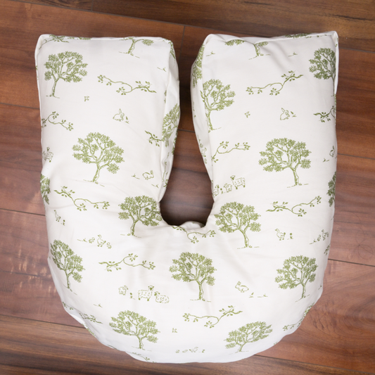White pregnancy back and lumbar support  pillow with green floral pattern on a wooden surface