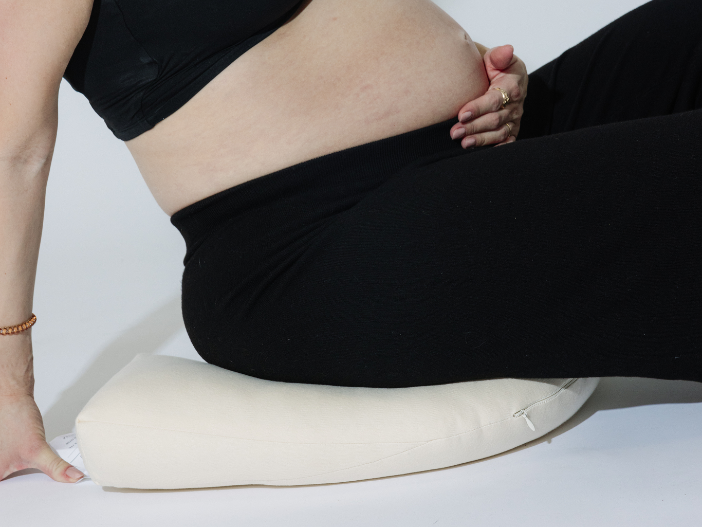 woman holding pregnant belly tush sitting on tush pillow for support